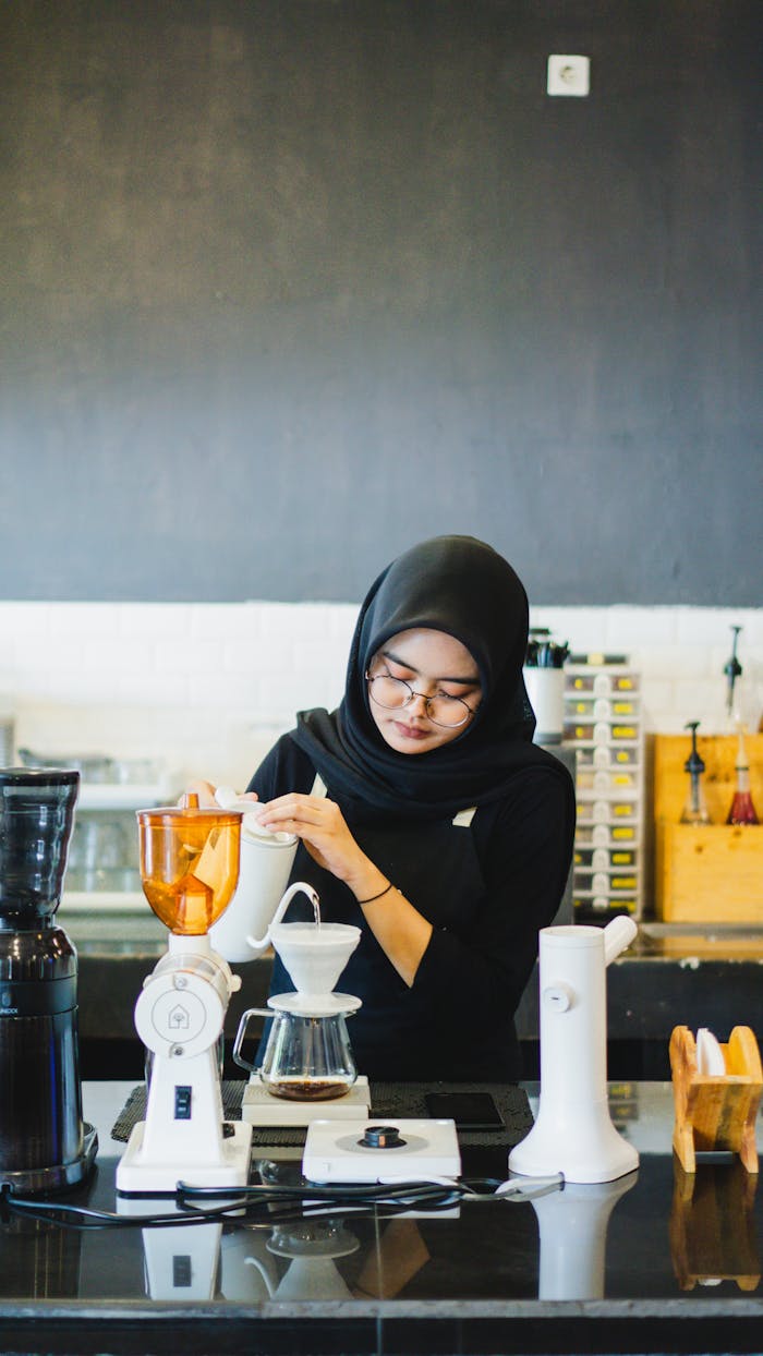 Barista in hijab brewing coffee in a Madiun café, Indonesia.
