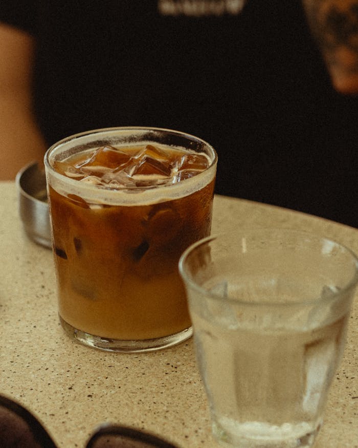 tentang-kami-01 Foto close-up es kopi di atas meja kafe di Tel Aviv, yang menangkap suasana perkotaan yang santai.