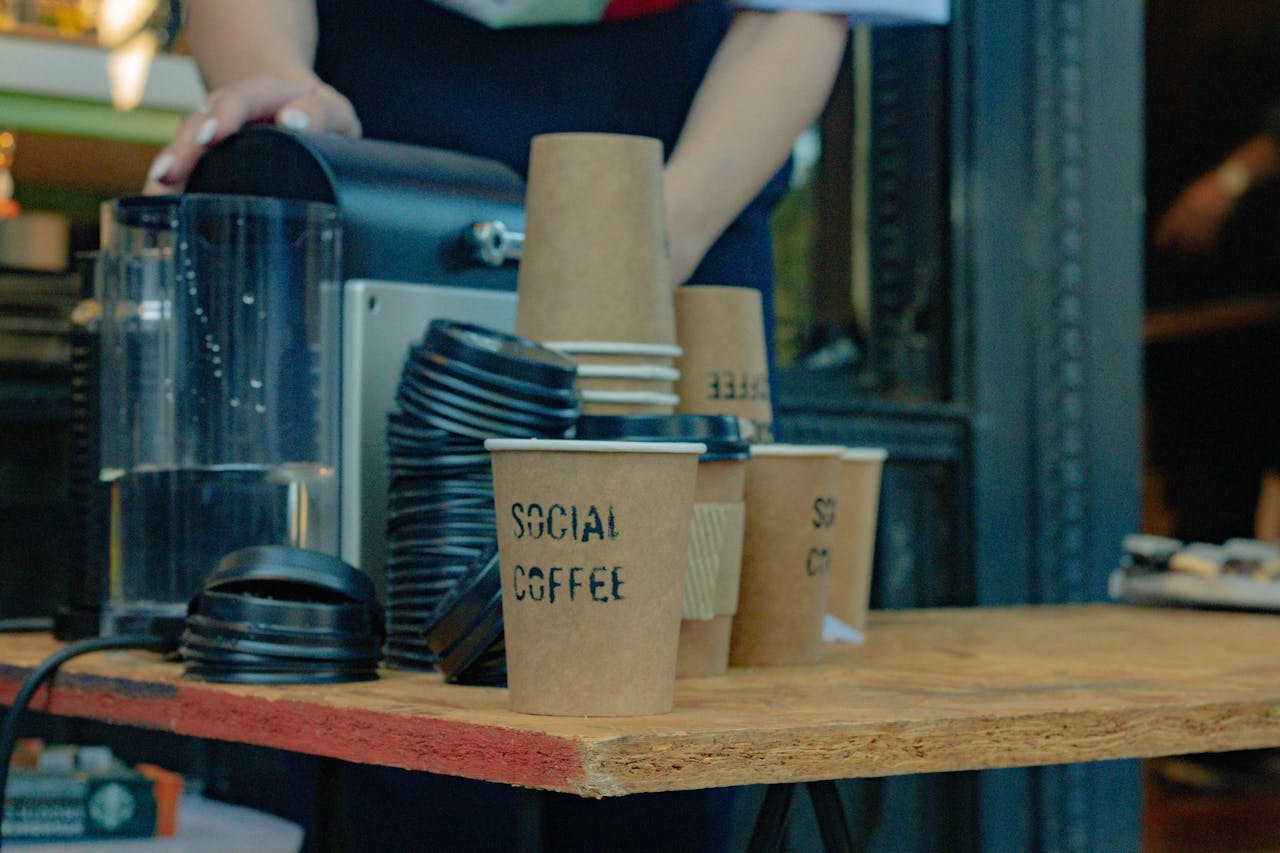 Gambar close-up seorang barista sedang menyiapkan kopi dengan cangkir untuk dibawa pulang ke sebuah kafe Argentina.